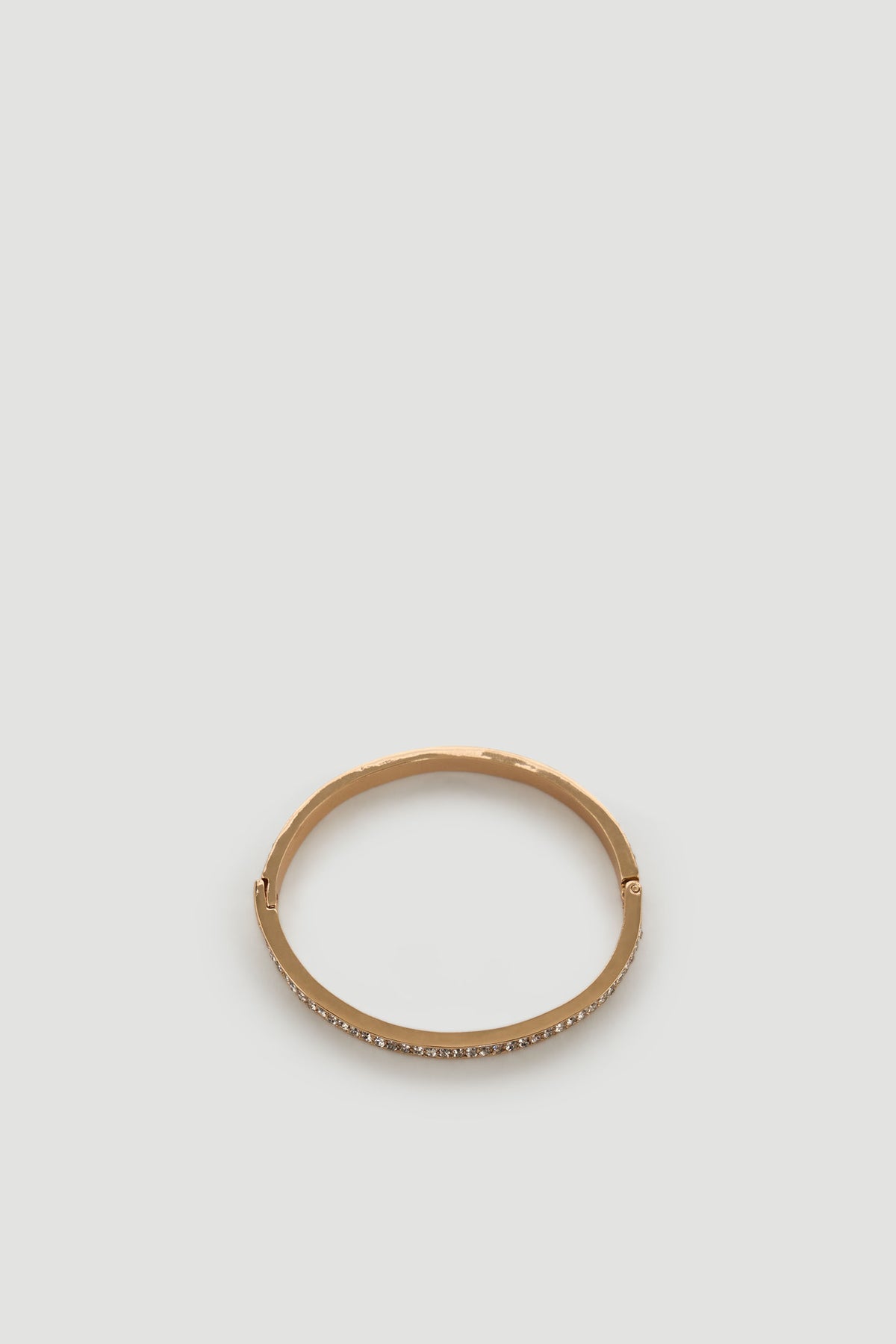 Gold-toned bracelet with a sleek band featuring a row of small sparkling diamante accents for an elegant touch.