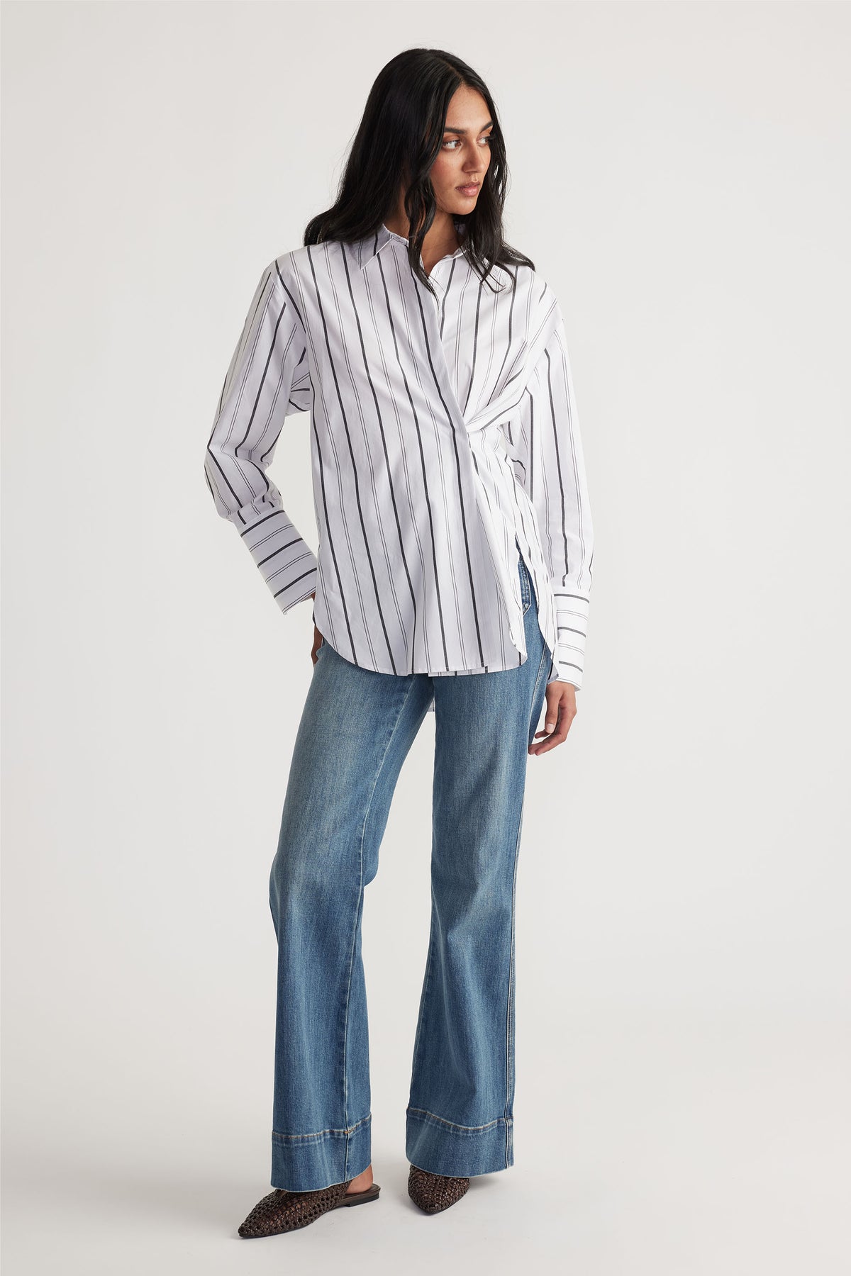 Model wears Ivy Button Shirt in portrait gallery shot one, styled with relaxed denim jeans, highlighting the shirt's unique side button detail.