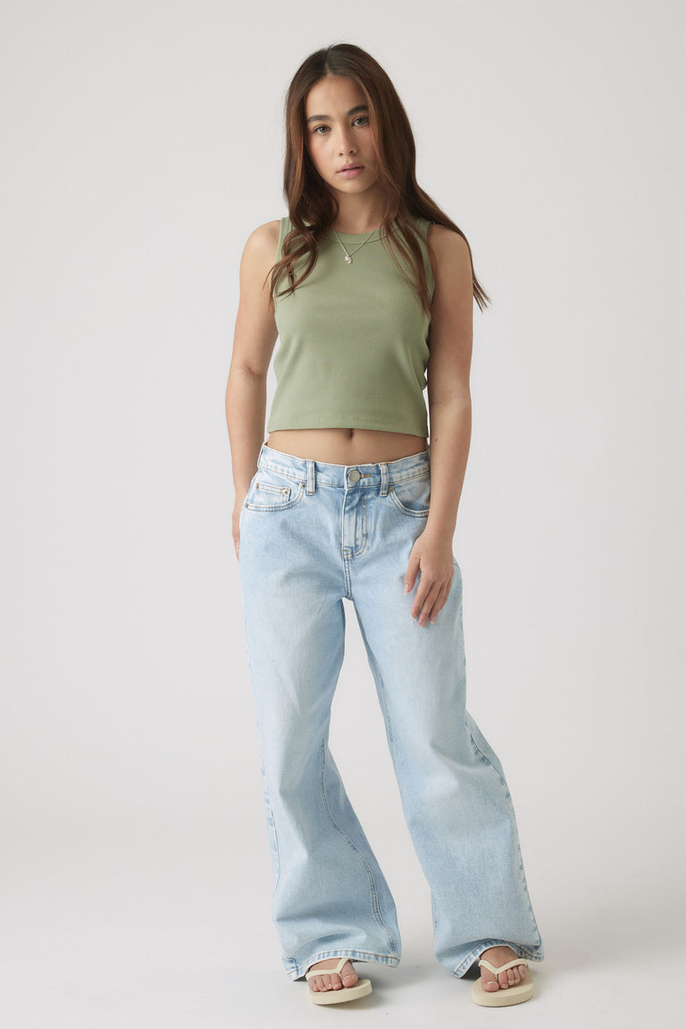 Teen girl wearing a sleeveless olive green cropped tank top paired with relaxed light wash wide-leg jeans and sandals