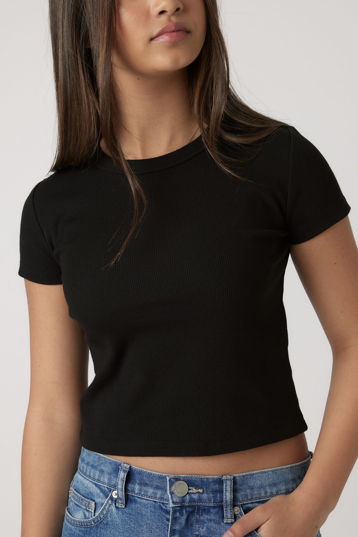 Teen girl wearing a fitted black crop tee paired with casual blue denim jeans for a laid-back look.