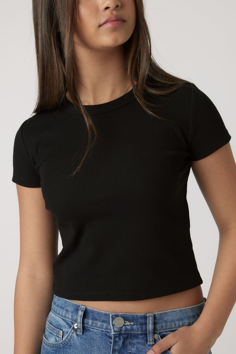 Teen girl wearing a fitted black crop tee paired with casual blue denim jeans for a laid-back look.