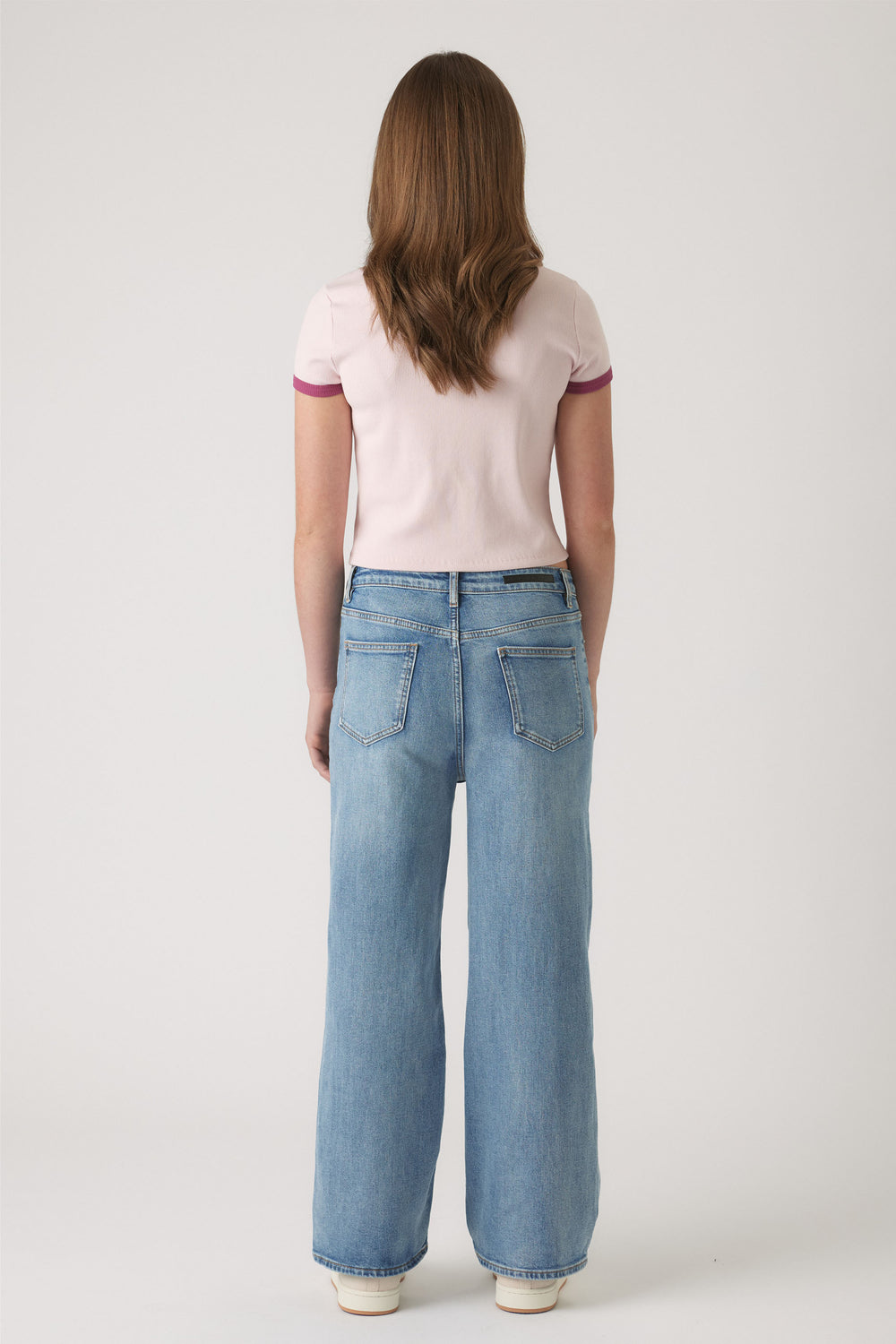 Girl wearing light blue wide-leg denim jeans paired with a pale pink cropped tee with contrasting sleeve trim