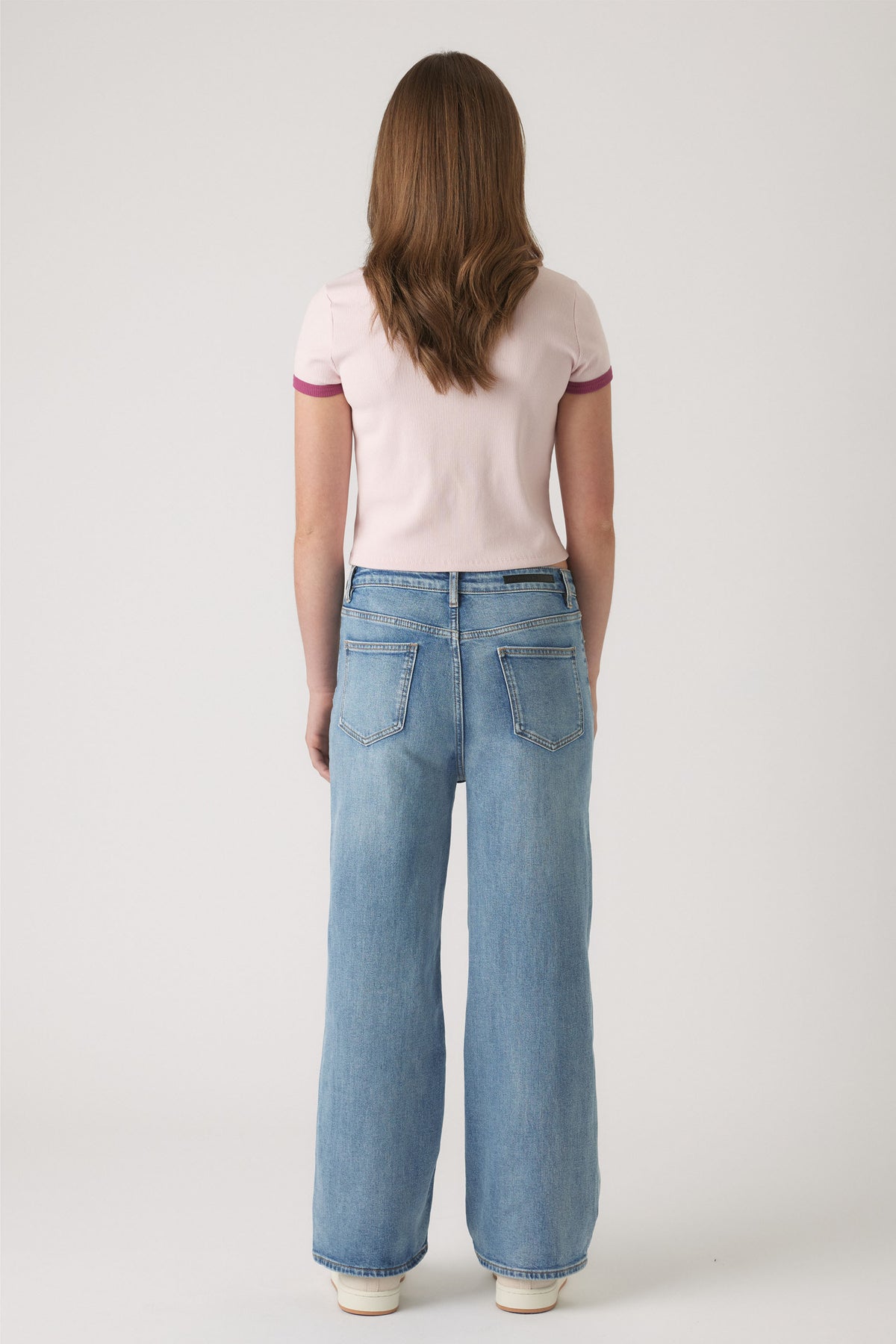 Girl wearing light blue wide-leg denim jeans paired with a pale pink cropped tee with contrasting sleeve trim