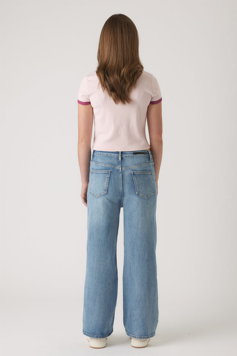 Girl wearing light blue wide-leg denim jeans paired with a pale pink cropped tee with contrasting sleeve trim