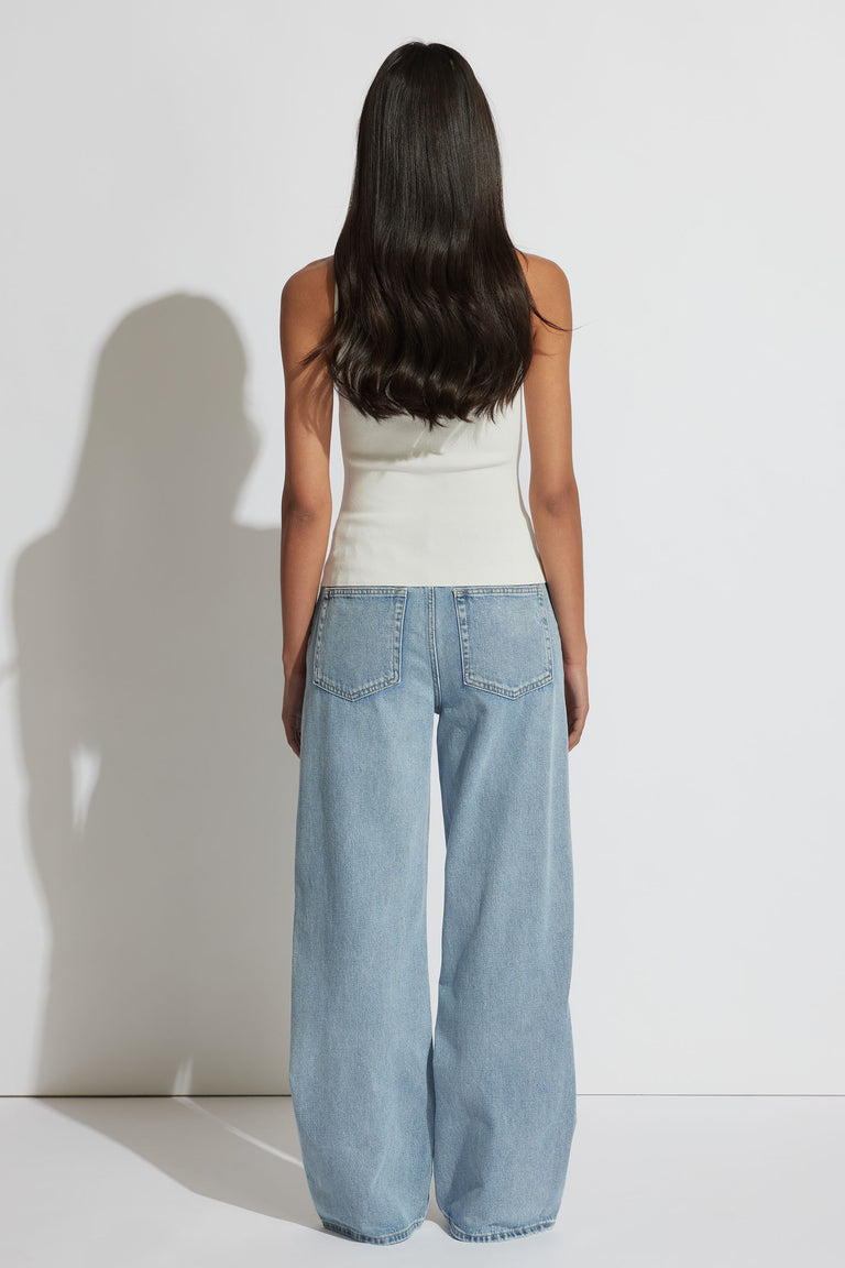 Woman seen from behind wearing an ivory square neck tank top paired with light blue wide-leg denim jeans