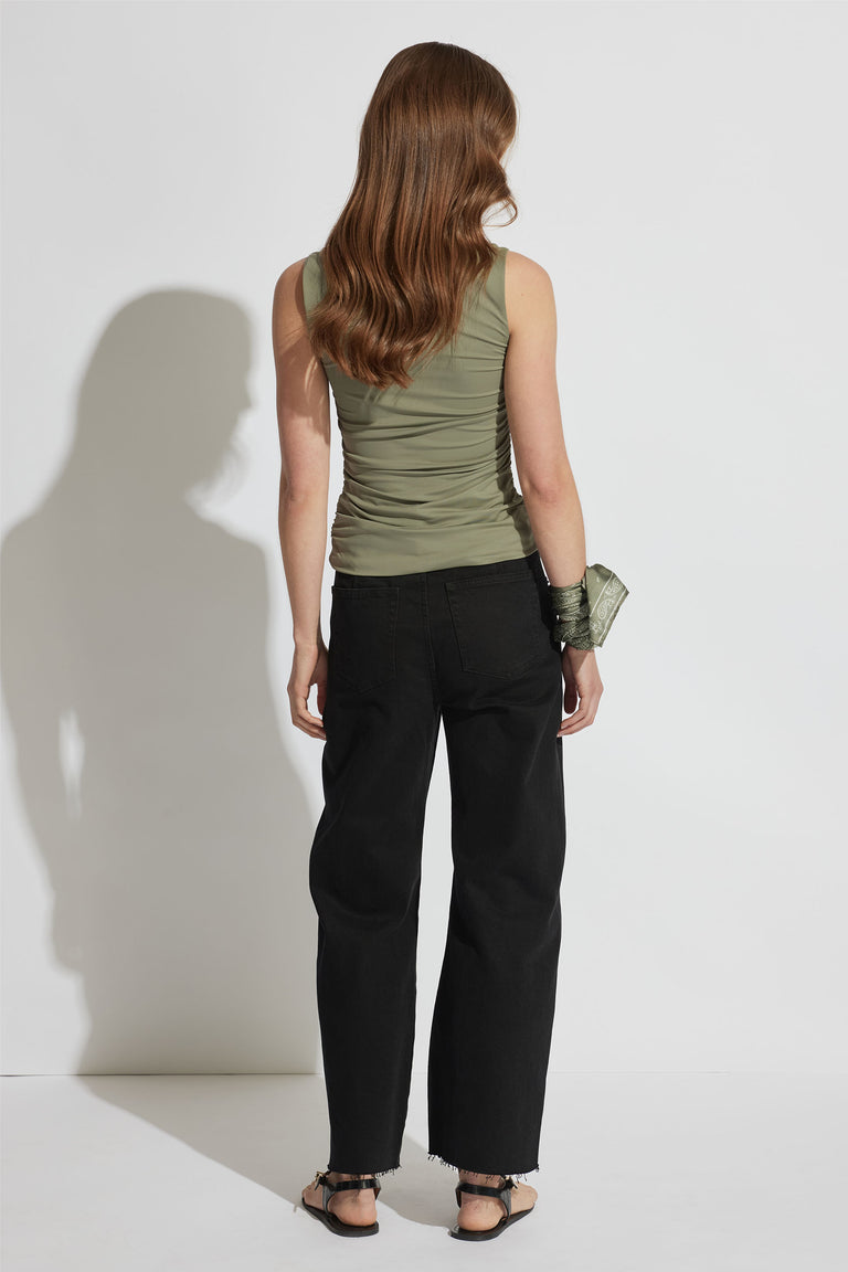 Girl wearing a fitted olive ruched top paired with relaxed black wide-leg jeans and flat sandals viewed from behind