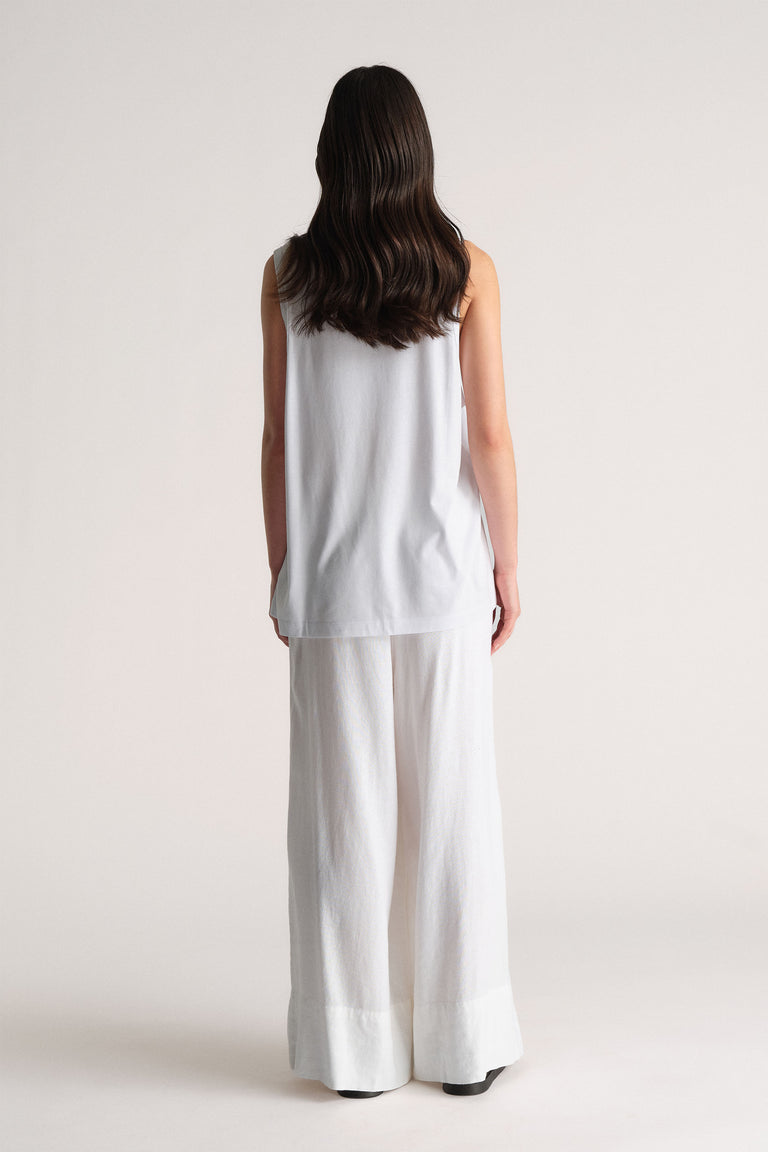 Woman shown from behind wearing a relaxed white sleeveless top paired with wide-leg white pants for a clean, casual look.