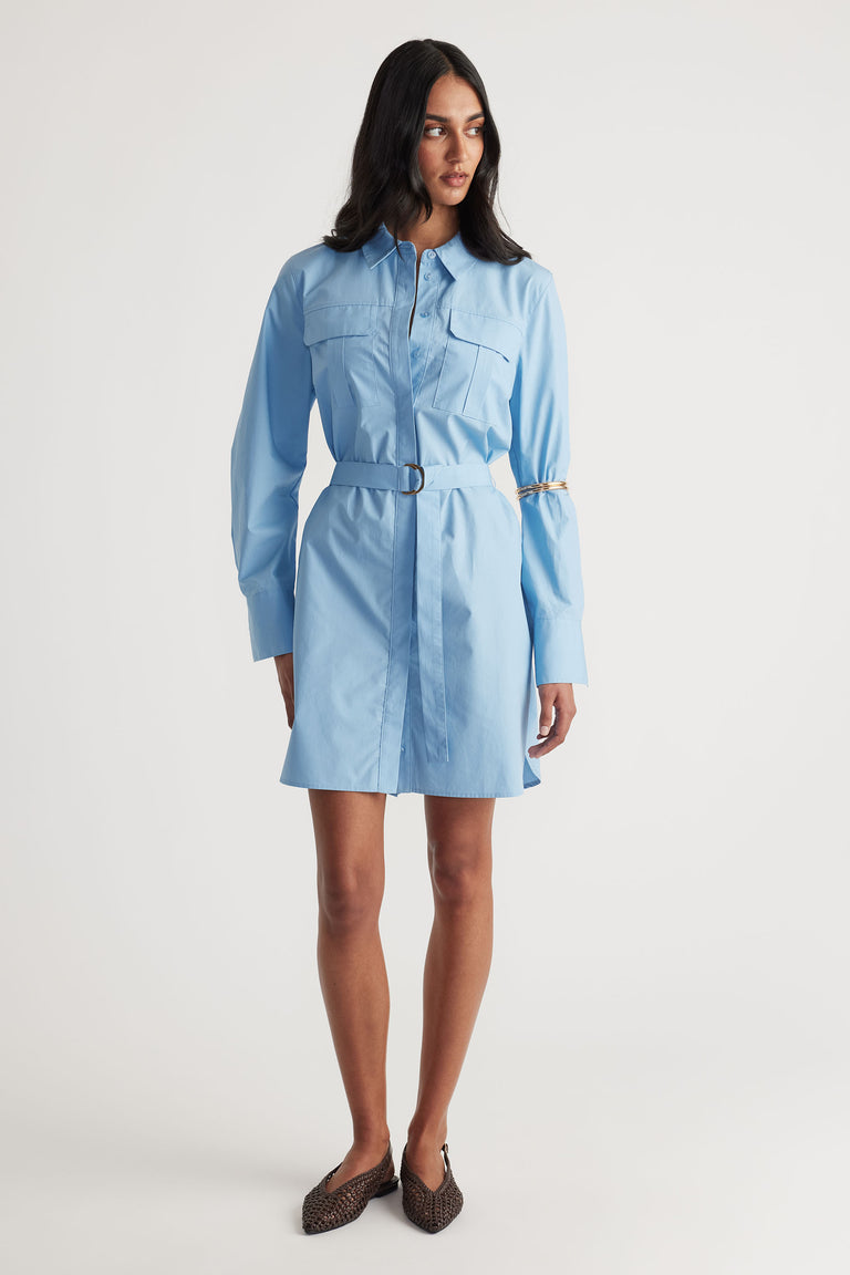 Woman wearing a belted sky blue mini shirt dress with long sleeves and flap chest pockets paired with woven pointed flats