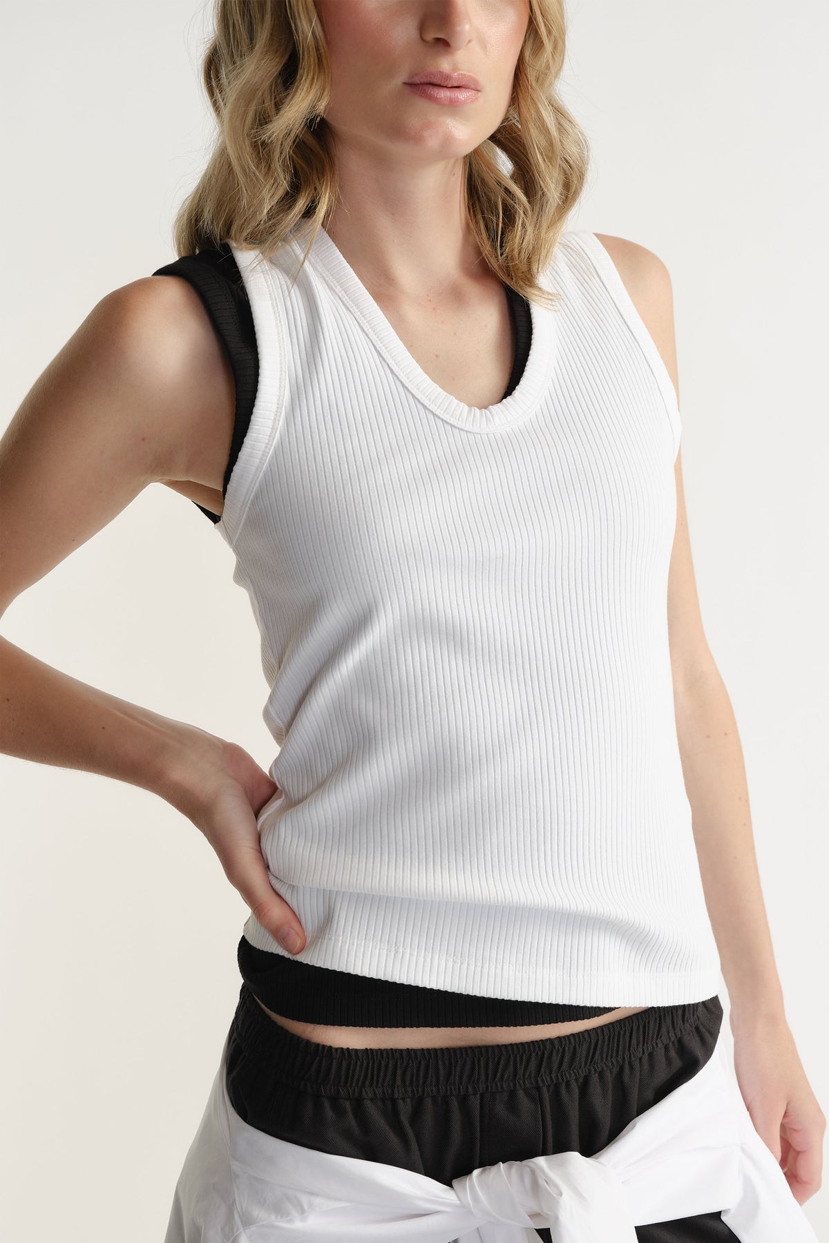 Woman wearing a fitted ribbed scoop neck tank layered over a black sleeveless top for a chic layered look