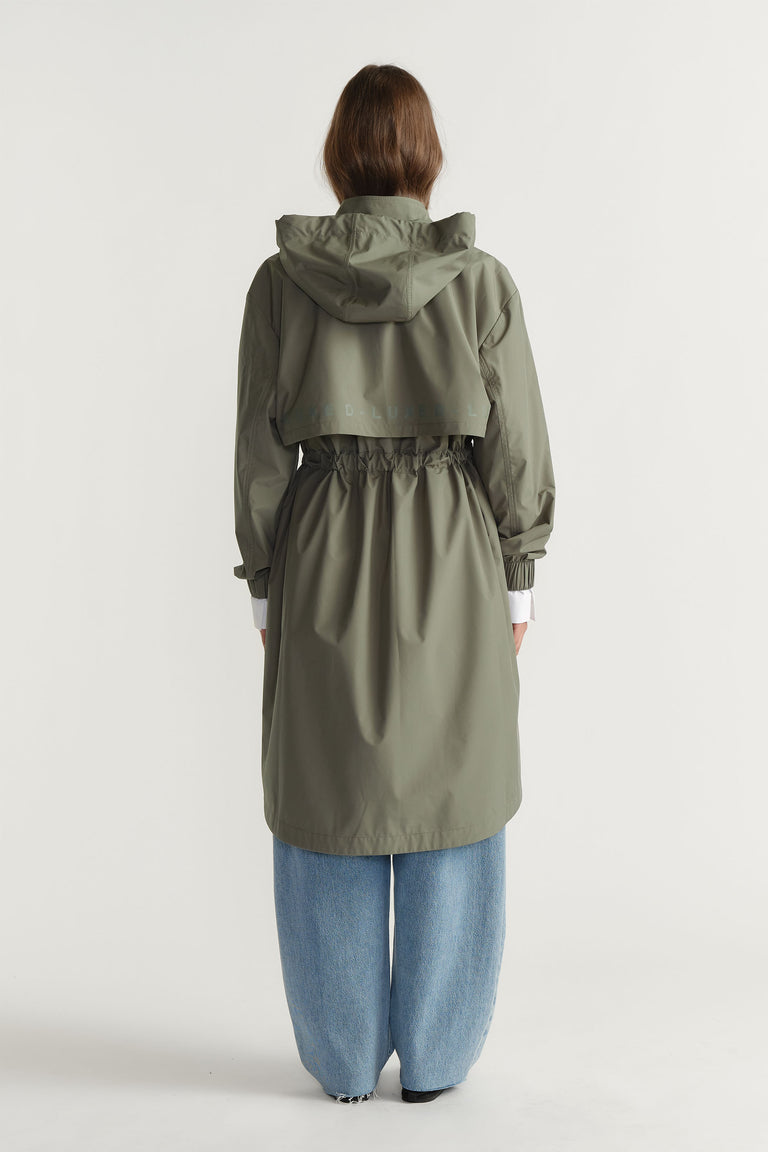 Back view of D-Luxe Rain Jacket in muted olive with hood and gathered waist styled with loose denim jeans by Decjuba