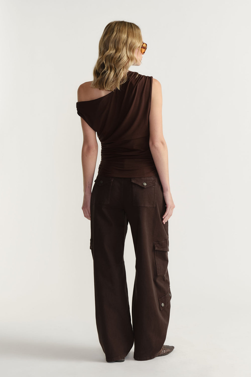 Woman standing in portrait view wearing Alexa Barrel Cargo Pant in dark brown, showing side cargo pockets and full length fit in gallery position 3