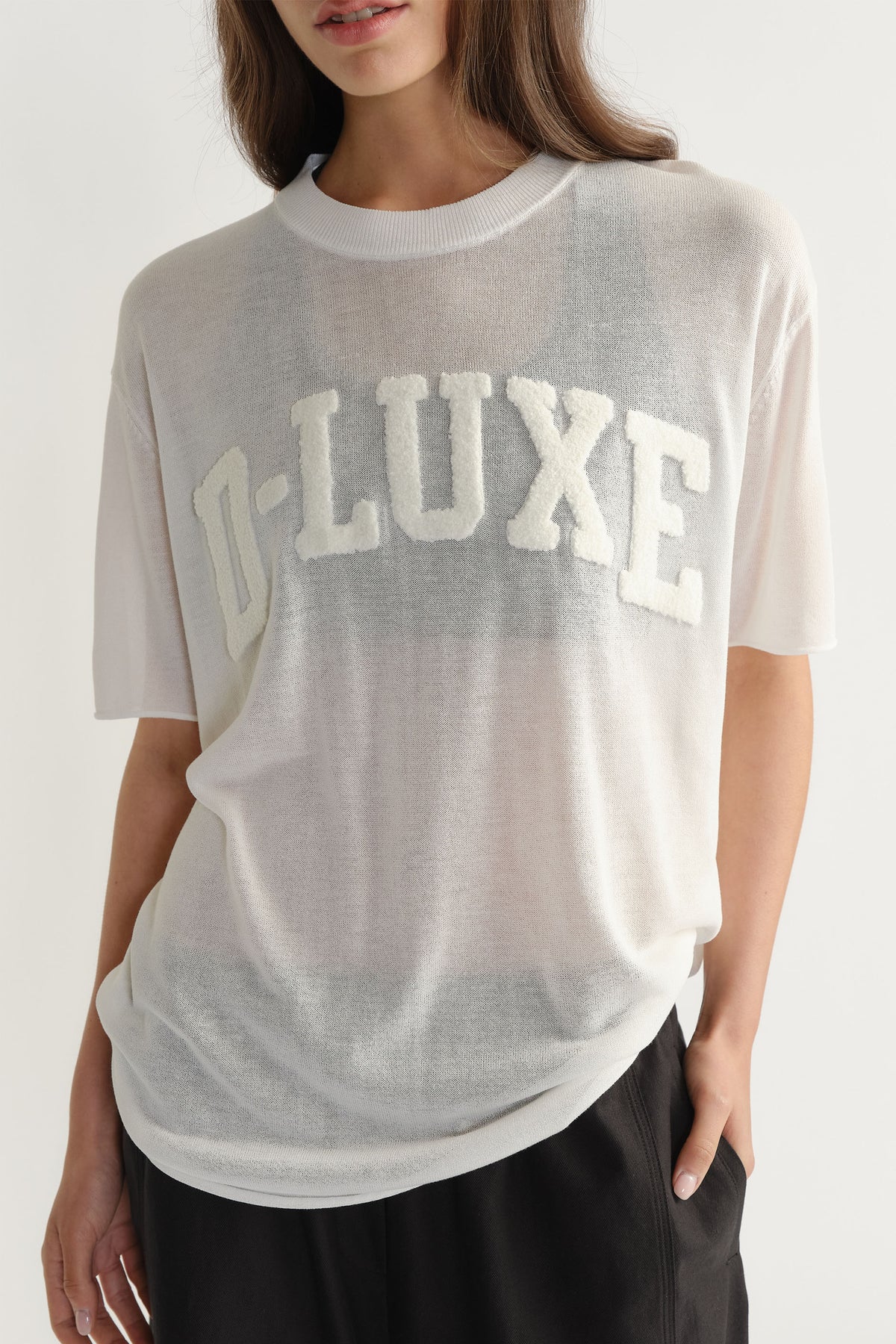 D-Luxe Fine Knit Tee in portrait gallery position two showing semi-sheer knitwear with bouclé lettering on chest