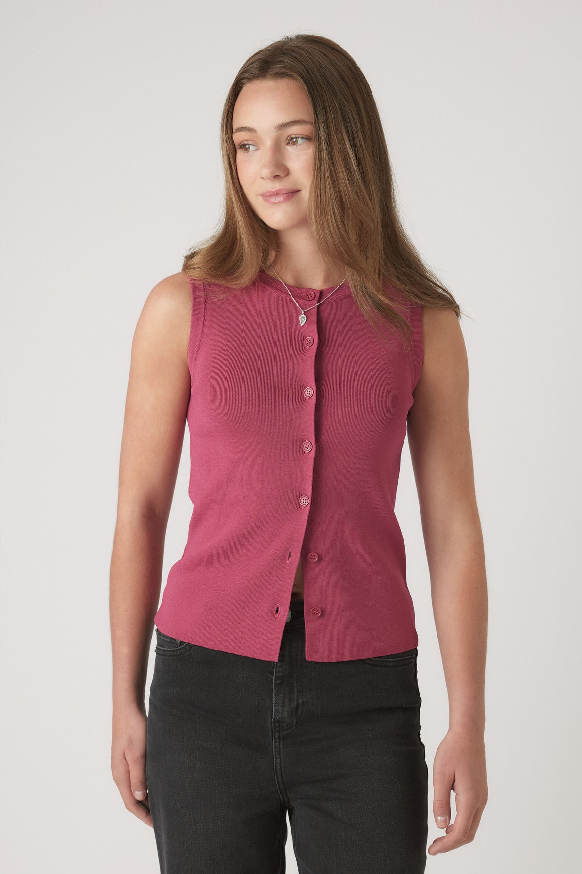 Teen girl wearing a sleeveless berry knit vest with button details, paired with black jeans and layered necklaces