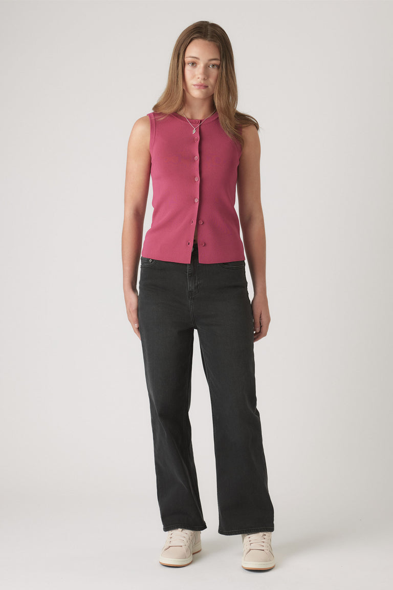 Teen girl wearing a raspberry knit sleeveless button-up vest paired with relaxed black jeans and cream sneakers