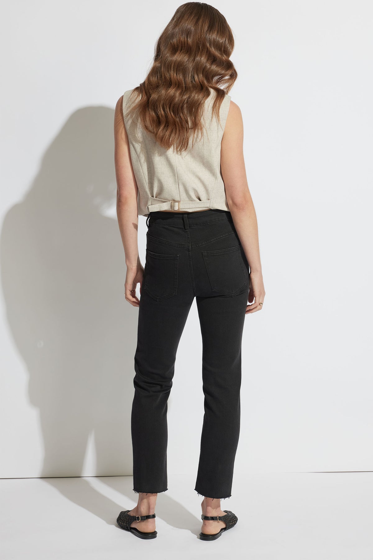 Woman wearing black Becky Straight Leg Jean with raw hem and high rise, pictured in portrait orientation, gallery position 3