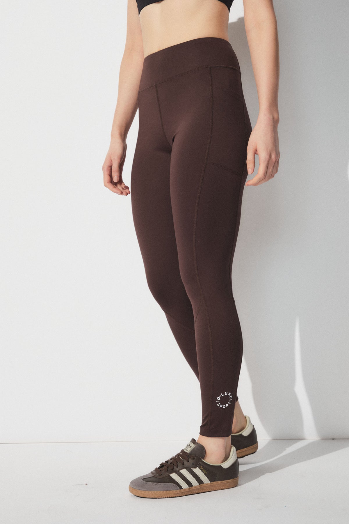 D-Luxe Stamp Legging in brown with phone pockets, mid-waisted fit, full length, shown in portrait gallery position 2.