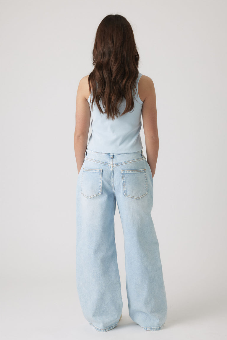 Rear view of girl wearing a pale blue sleeveless top paired with relaxed light wash wide-leg jeans