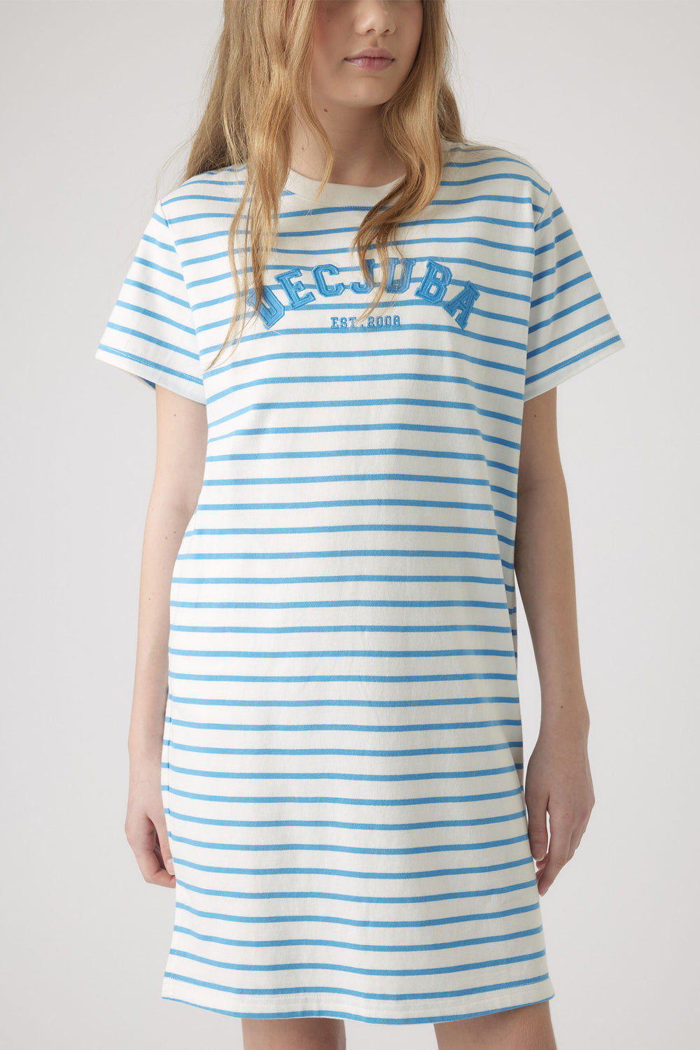 Girl wearing a casual white tee dress with light blue stripes and embroidered lettering on the chest for a sporty look