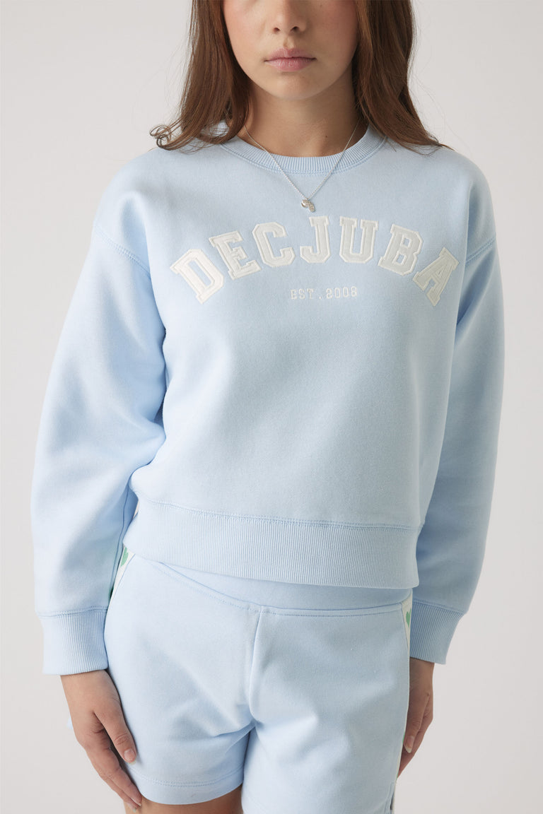 Girl wearing a pale blue sweatshirt with white logo lettering paired with matching shorts for a relaxed, casual look.
