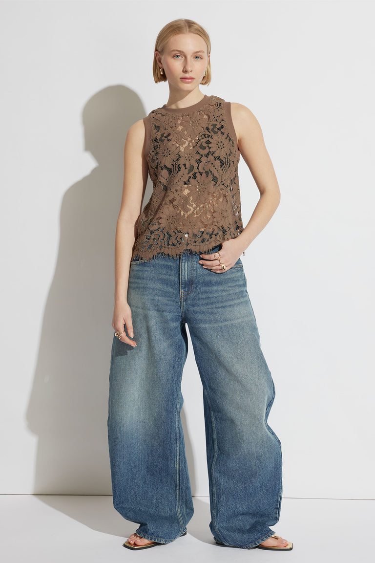 Woman wearing a cappuccino lace sleeveless tank paired with wide-leg blue denim jeans and sandals