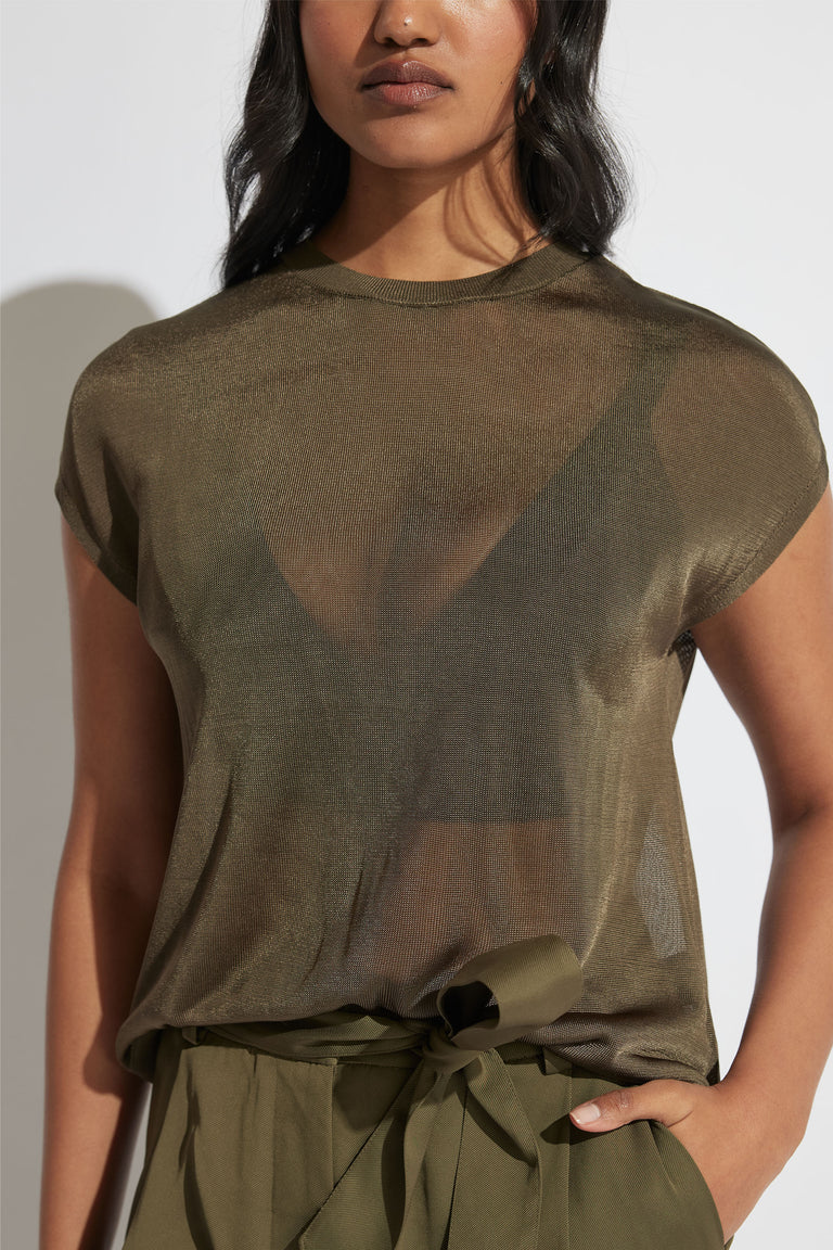Woman wearing a relaxed fit, lightweight olive knit tee with short sleeves and a crew neck paired with high-waisted pants.