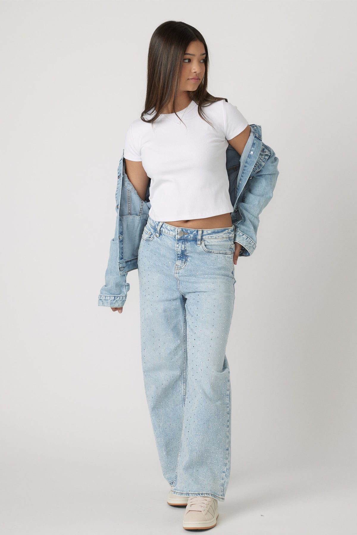 Teen girl wearing Girls Harper Crop Tee in white styled with light blue denim jeans and denim jacket by Decjuba Australian brand