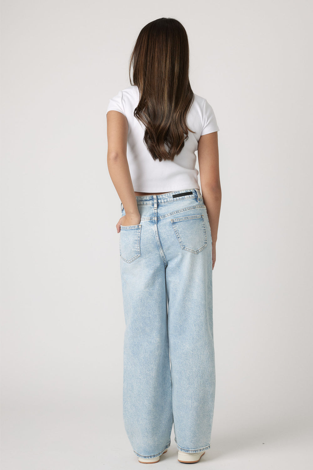 Girl wearing a white Girls Harper Crop Tee paired with light blue wide-leg jeans by Decjuba Australian fashion brand