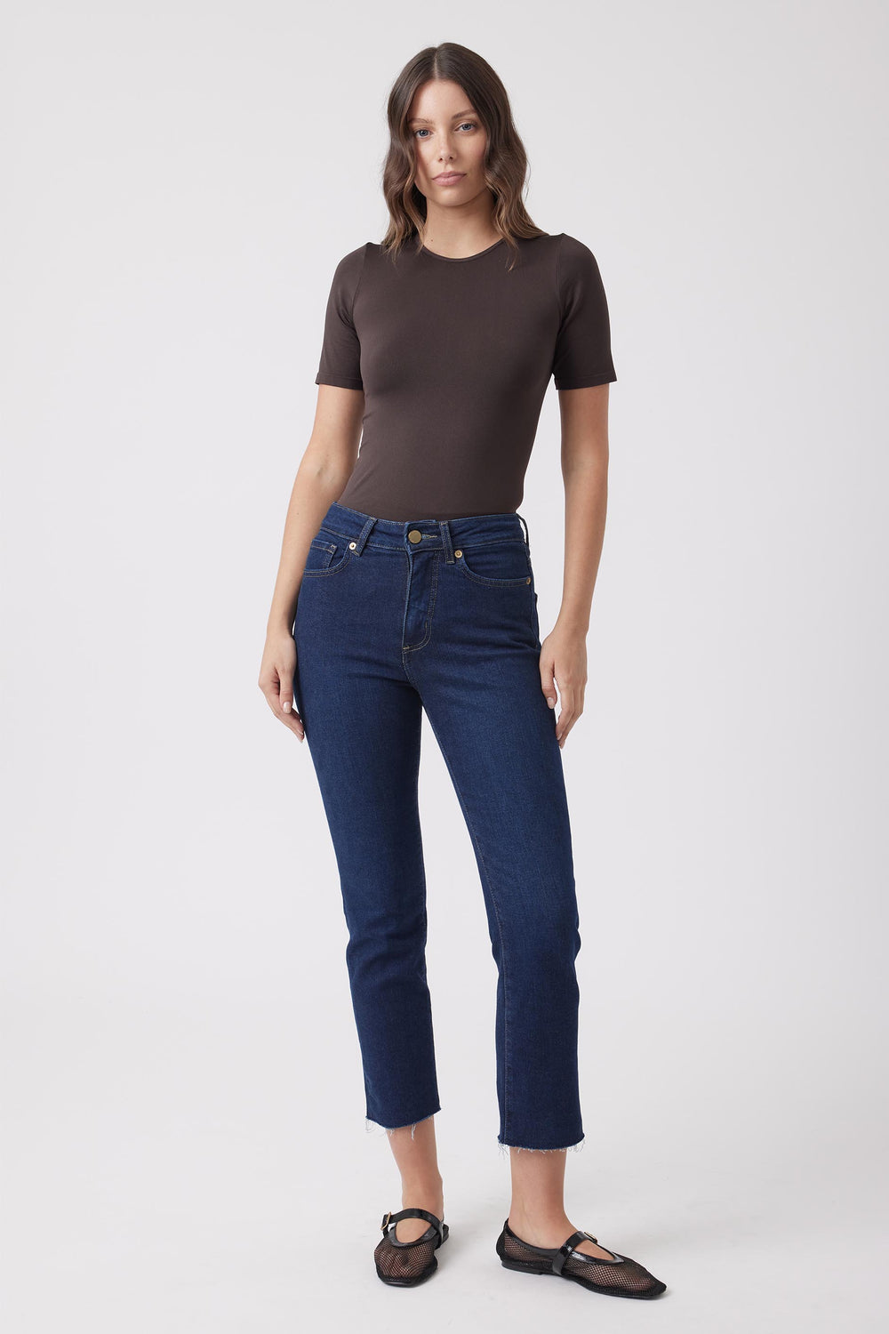 Woman wearing a dark brown fitted short sleeve tee with dark blue jeans