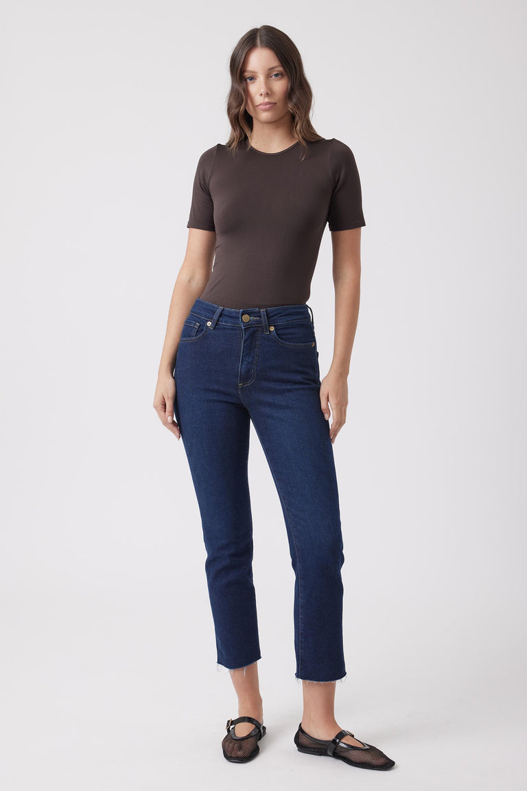 Woman wearing a dark brown fitted short sleeve tee with dark blue jeans