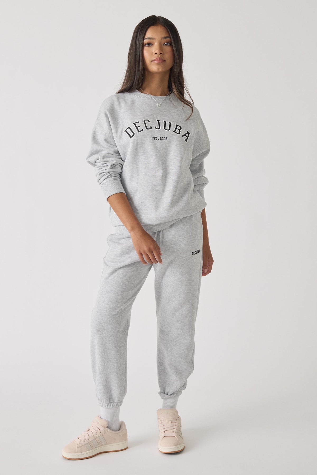 Teen girl wearing light grey trackpants and matching sweatshirt with casual sneakers in relaxed pose