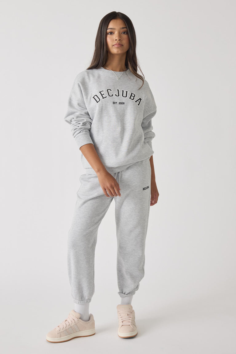 Teen girl wearing light grey trackpants and matching sweatshirt with casual sneakers in relaxed pose