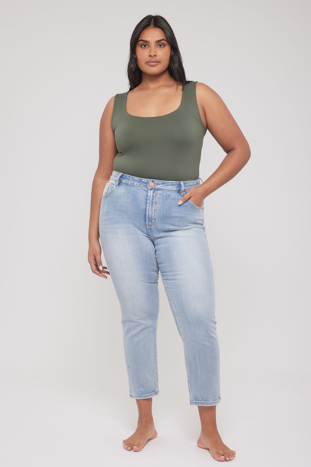 Model wearing an olive green scoop neck tank top with light blue jeans