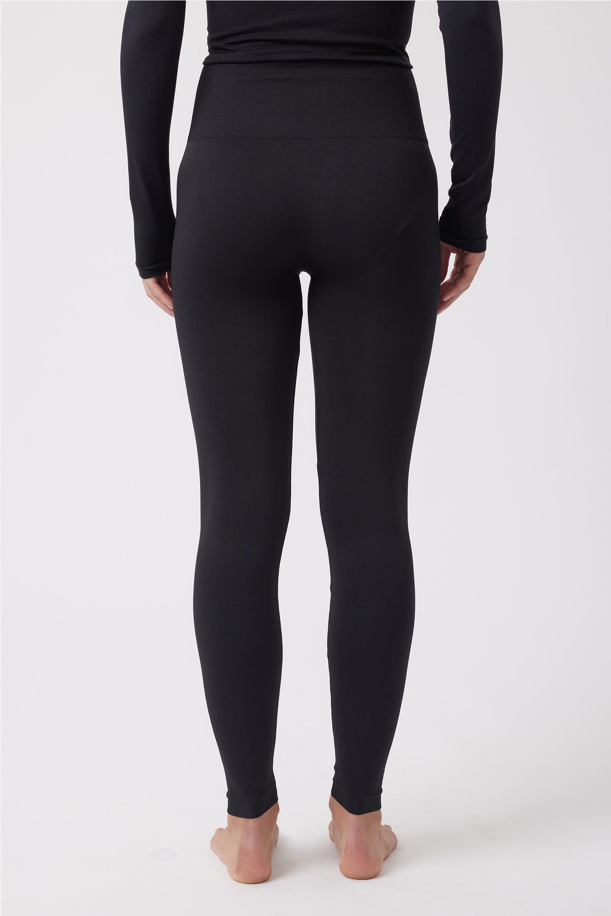 Back view of woman wearing fitted black seamless leggings with a high waistband and long-sleeve top