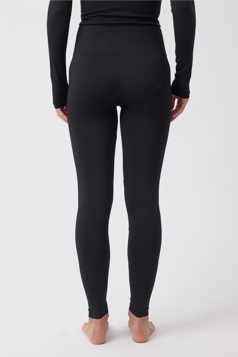 Back view of woman wearing fitted black seamless leggings with a high waistband and long-sleeve top