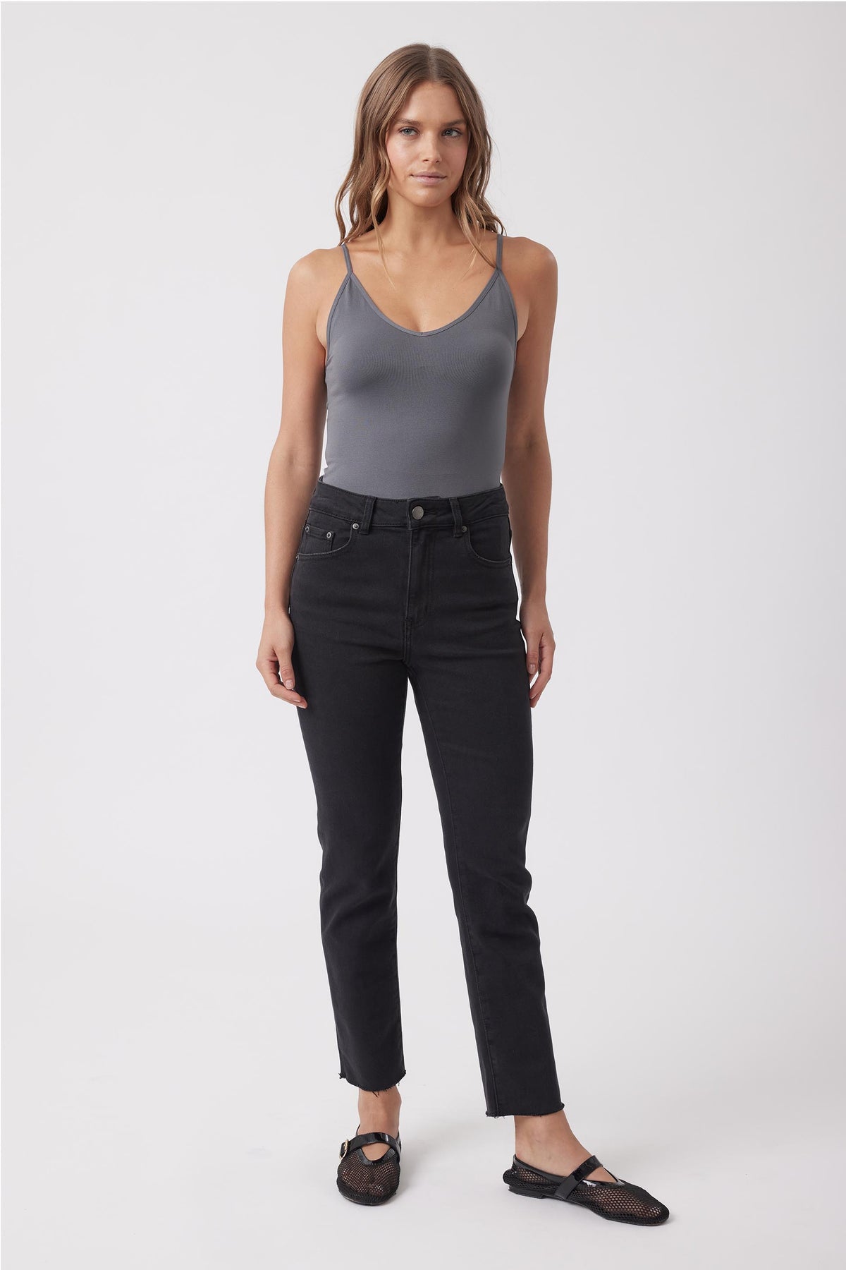 Woman wearing a grey fitted V neck tank top with black jeans and sandals