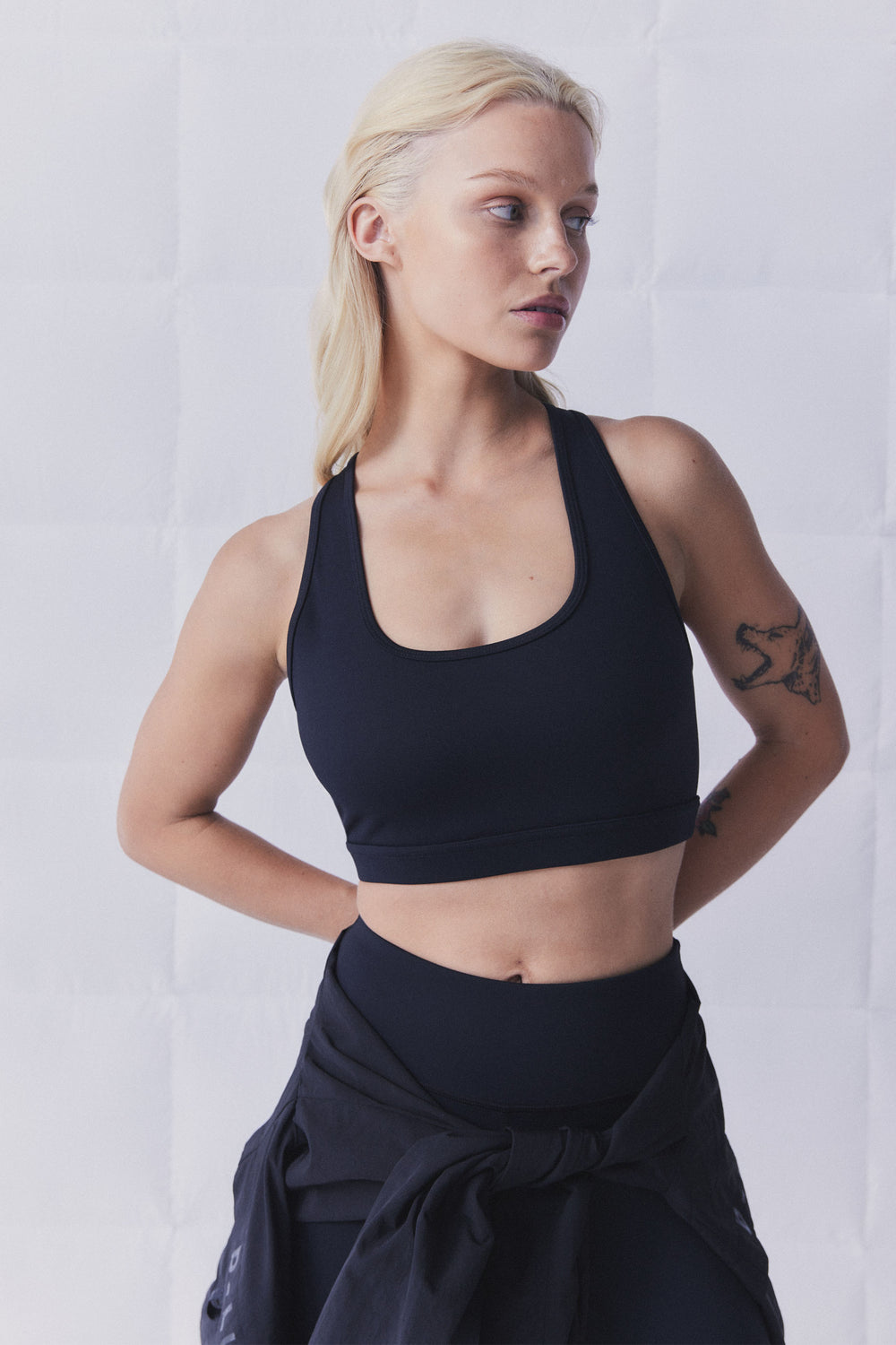 Woman wearing a black racerback sports bra with a scoop neckline