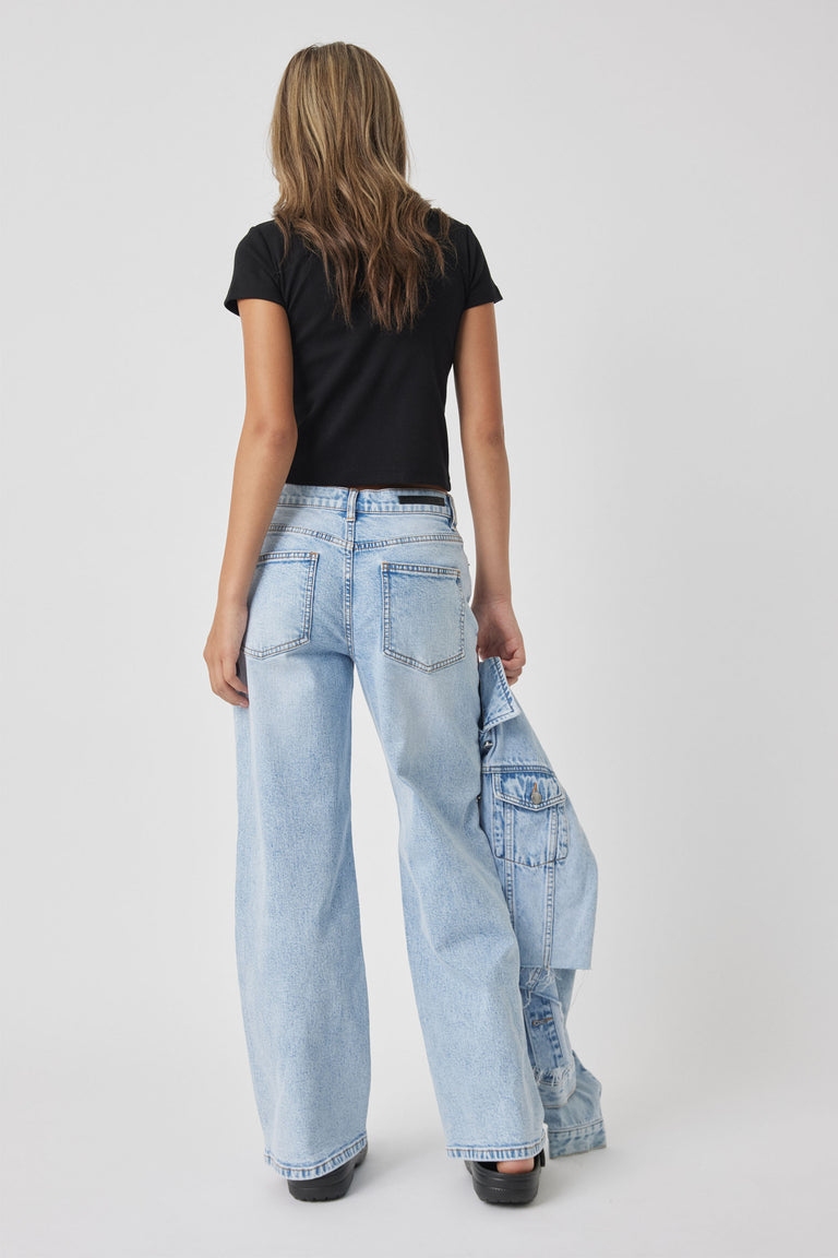 Teen girl wearing a fitted black crop top paired with light blue wide-leg denim jeans, holding a matching denim jacket.