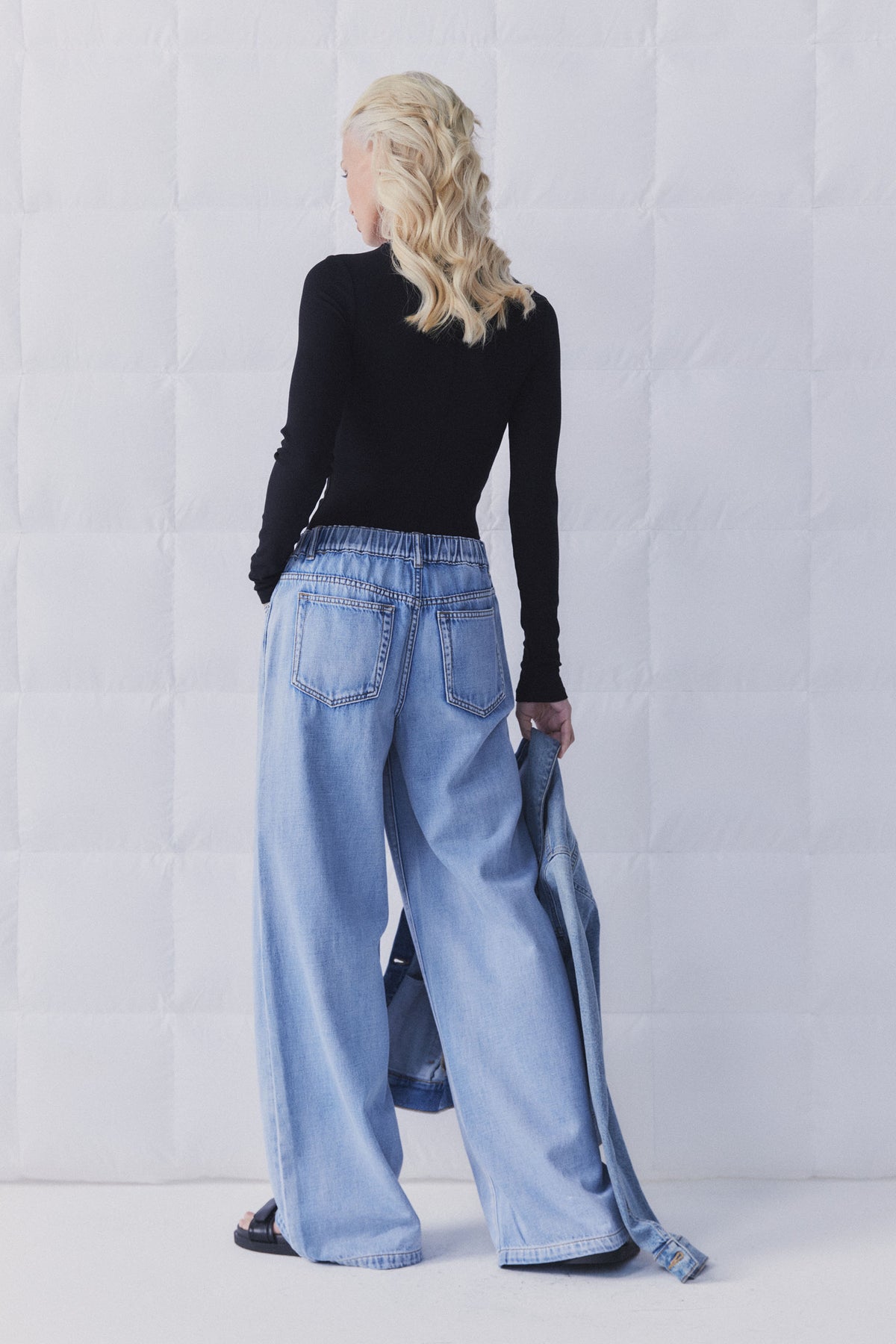 Woman wearing D-Luxe Wide Leg Jean with elastic waistband, shown from back in gallery position 5, portrait orientation.