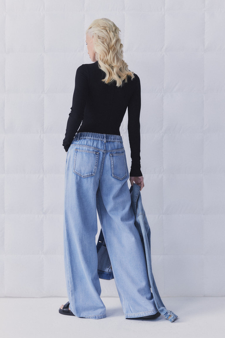 Woman wearing D-Luxe Wide Leg Jean with elastic waistband, shown from back in gallery position 5, portrait orientation.