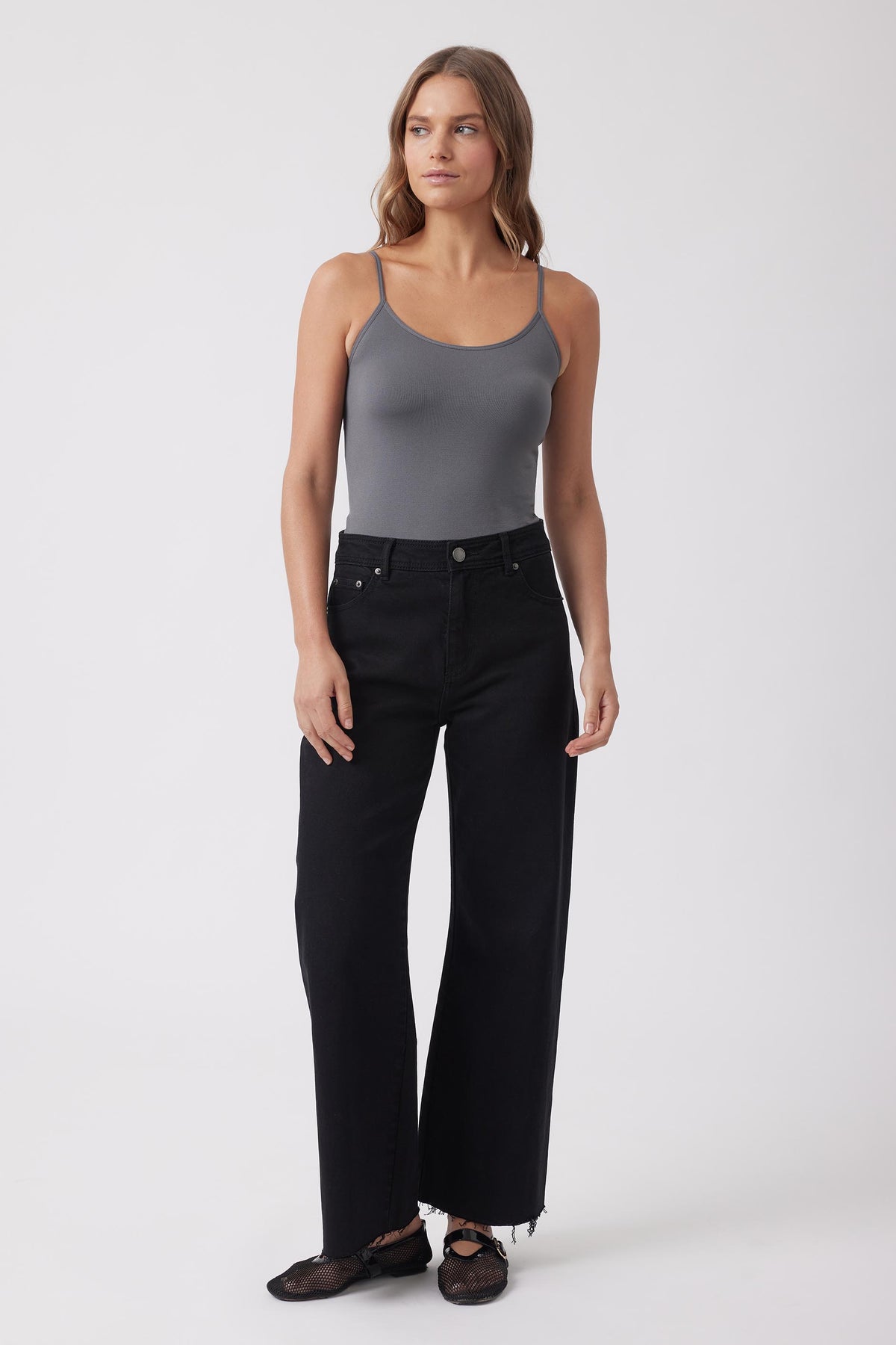 Woman wearing a grey seamless thin strap tank and black wide leg jeans
