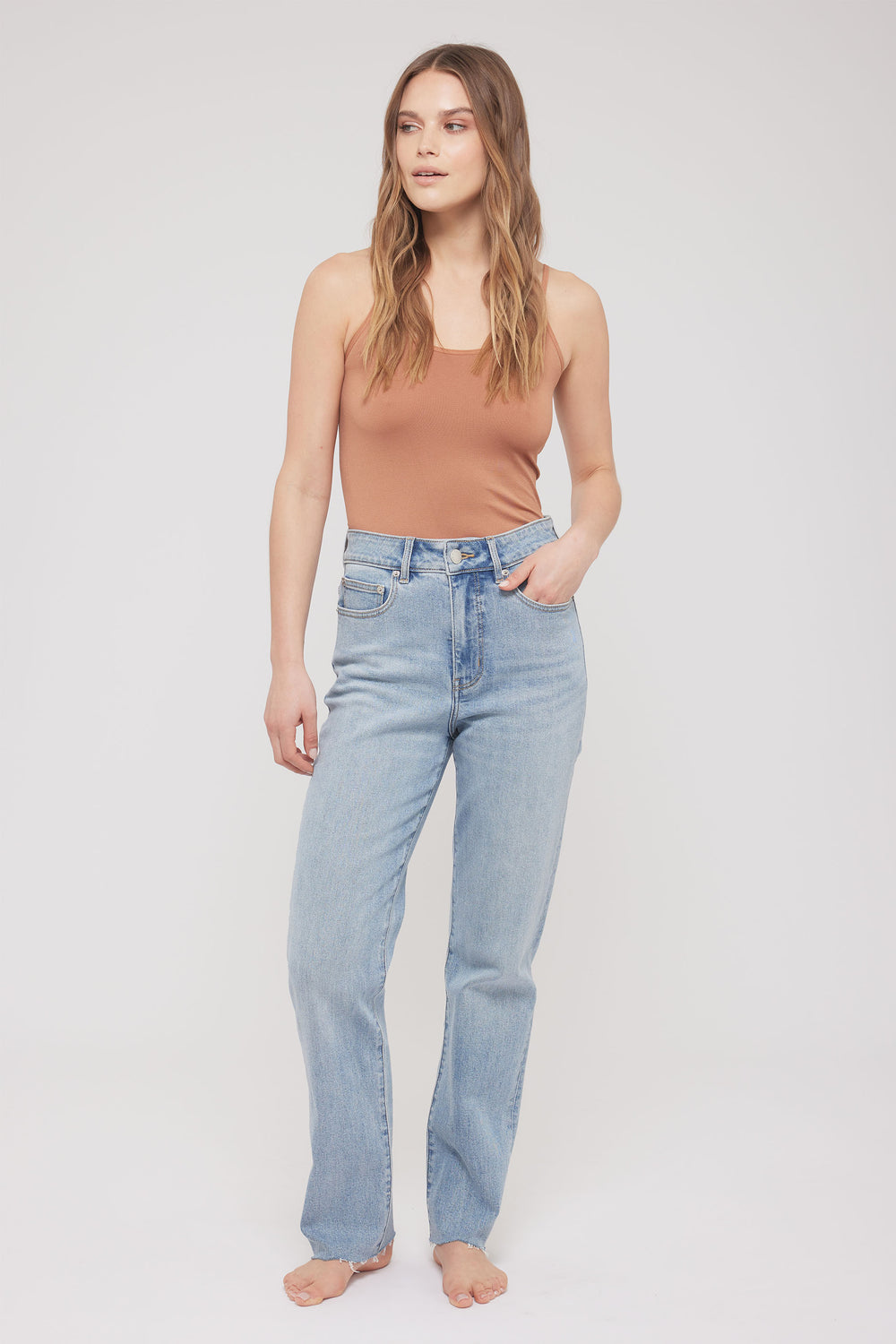 Woman wearing a brown thin strap tank with light blue jeans