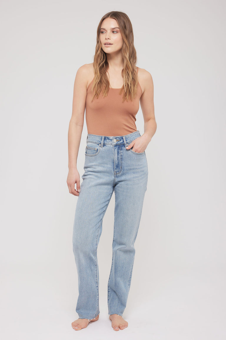Woman wearing a brown thin strap tank with light blue jeans