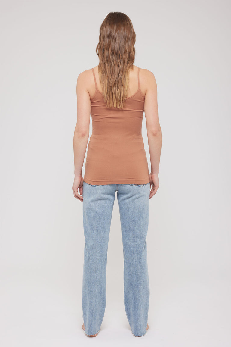 Woman viewed from behind wearing a brown thin strap tank top and light blue jeans