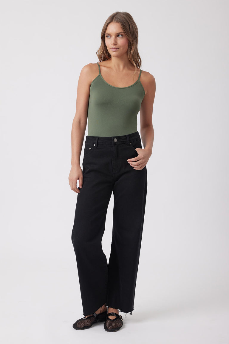 Model wearing an olive green thin strap tank with black wide leg jeans and flat shoes