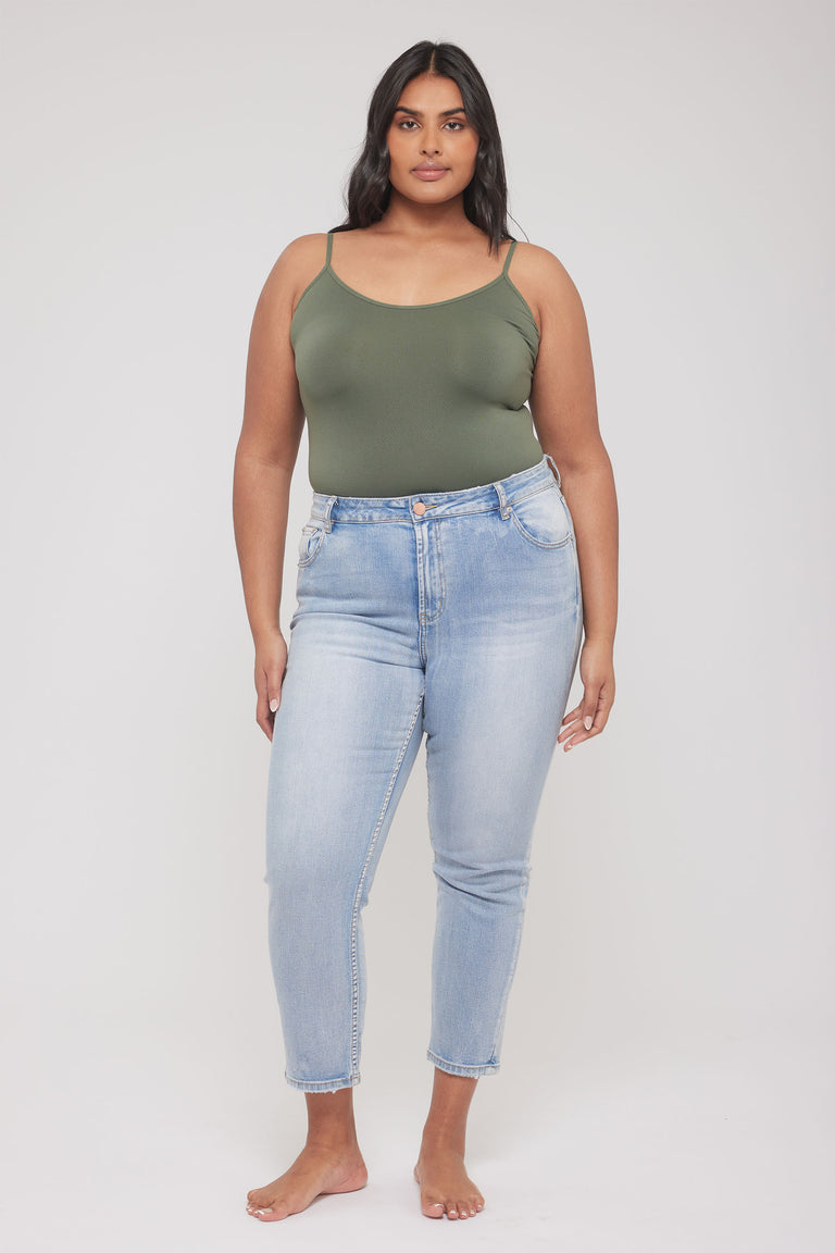 Model wearing an olive green thin strap tank top with light wash high waisted jeans