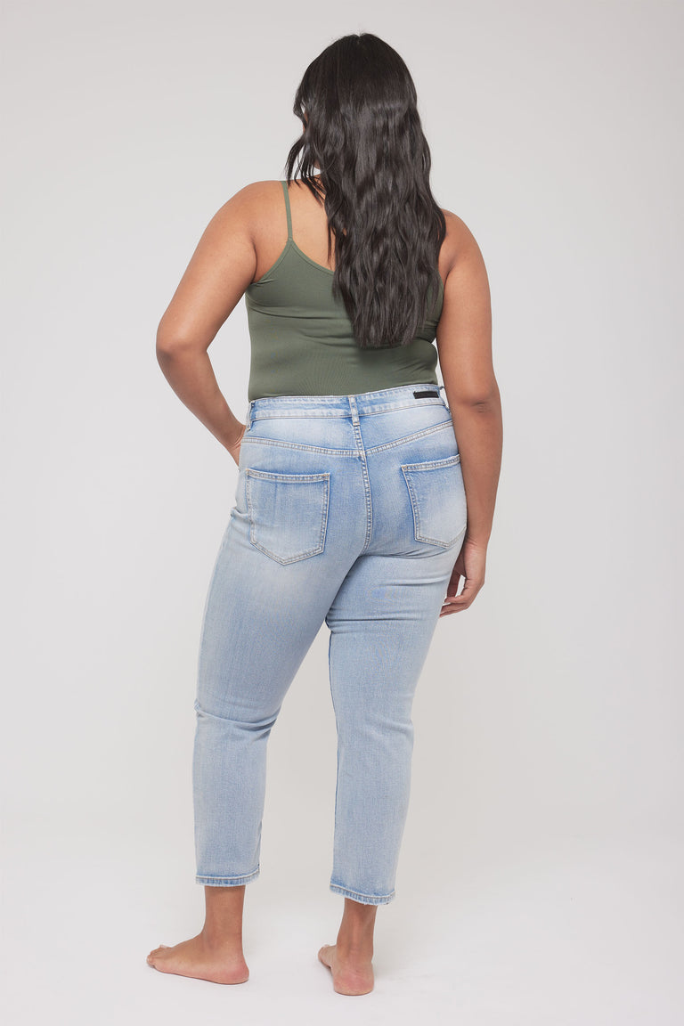 Woman wearing an olive thin strap tank and light wash jeans shown from the back