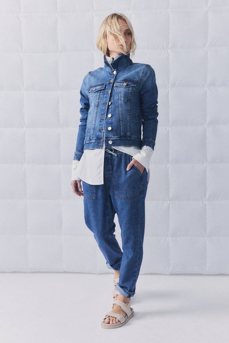 Woman wearing relaxed fit blue denim joggers paired with a classic denim jacket and layered white long sleeve top