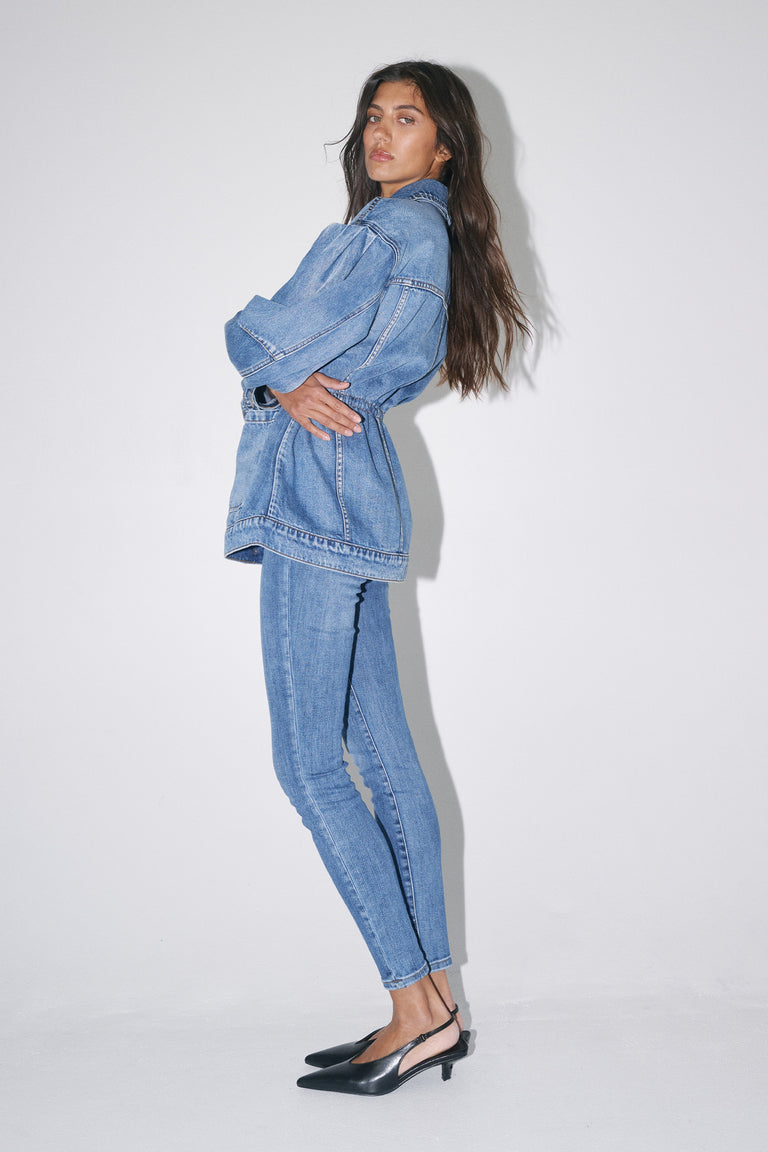 Woman wearing blue high-rise skinny jeans with a matching denim jacket and black heels
