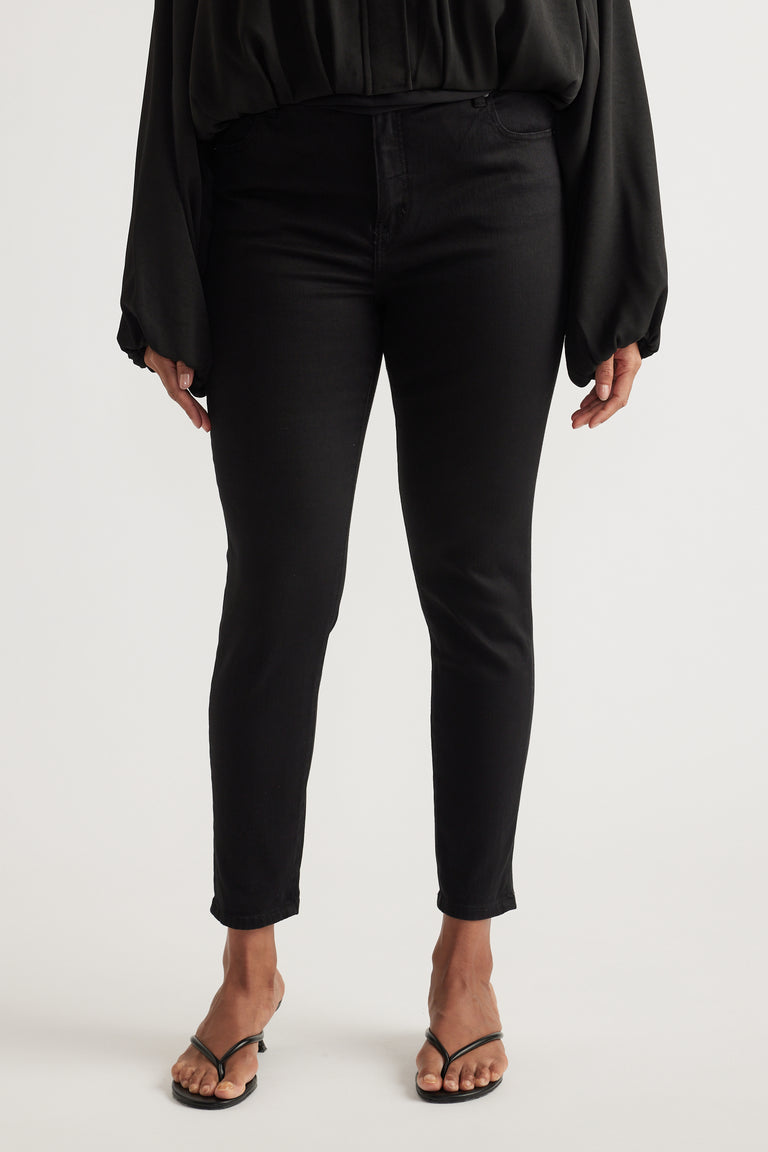 Woman wearing black high-rise skinny ankle jeans with a black blouse and strappy sandals