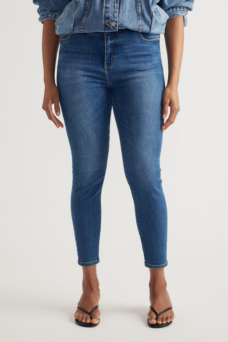 Woman wearing high rise blue skinny jeans with ankle-length hems and a denim jacket